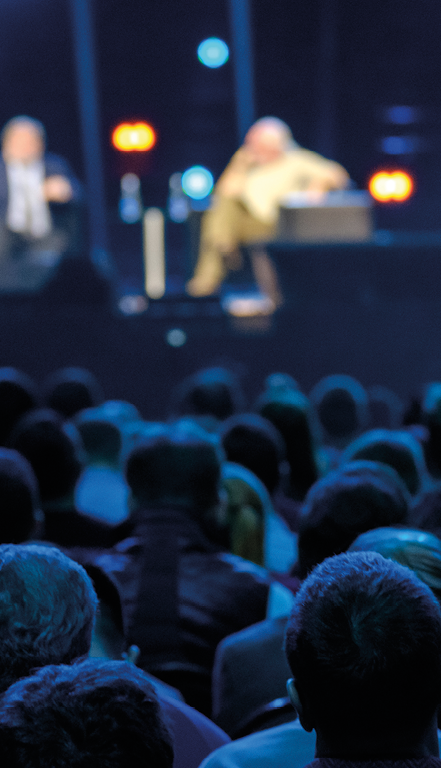 Audience listens to the lecturer at the business conference, back view, blue tones