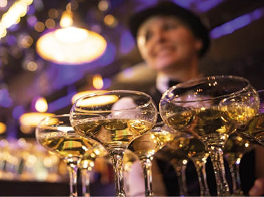 happy waitress holding a tray full of glasses or welcome drinks at an event